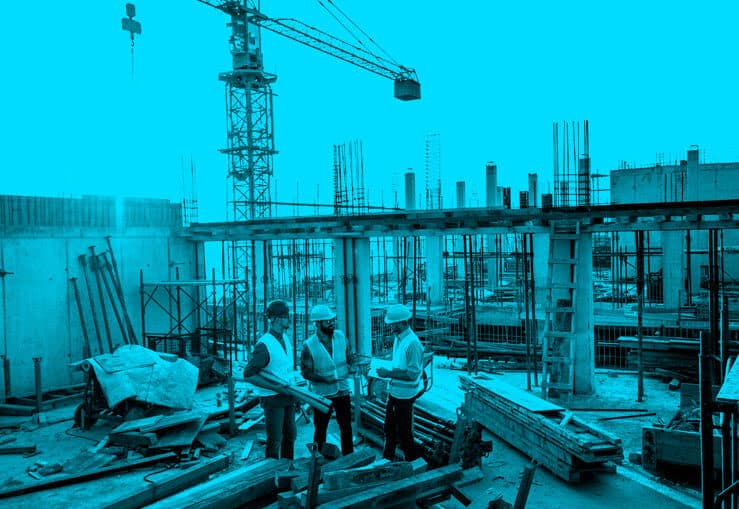 Construction workers talking on top of an incomplete building.