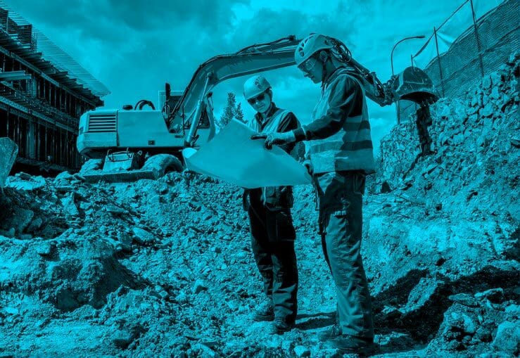 Two construction workers looking at plans on a paper.